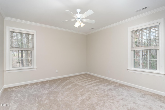 carpeted empty room with visible vents, baseboards, a ceiling fan, and crown molding