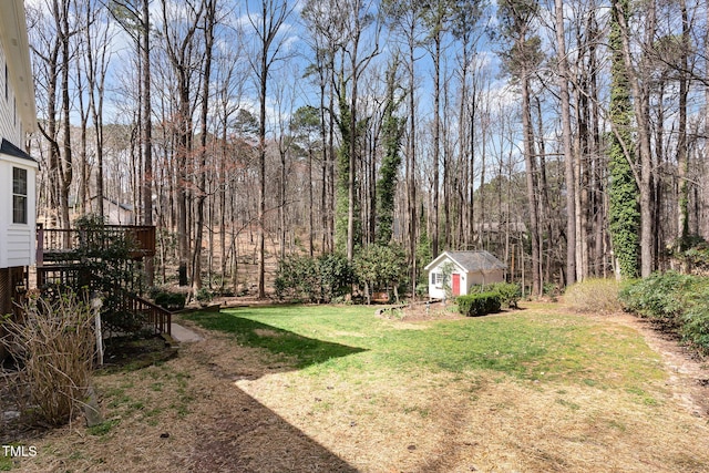 view of yard featuring an outbuilding, stairway, a forest view, and a deck