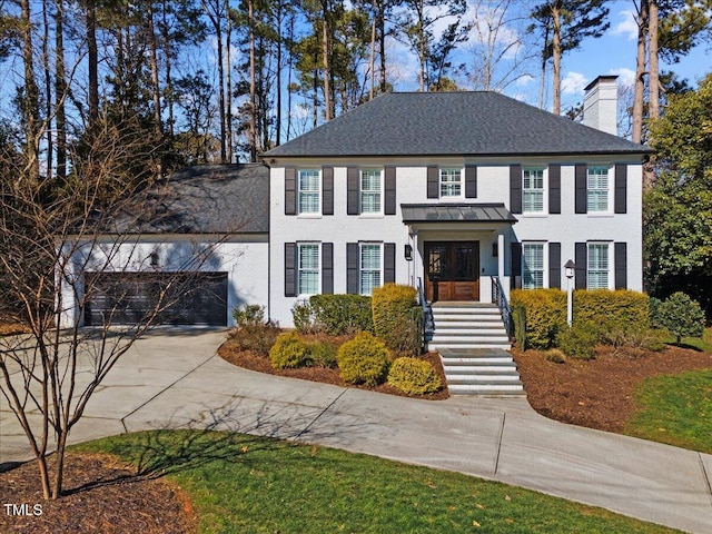 view of front of home featuring concrete driveway, a chimney, and an attached garage