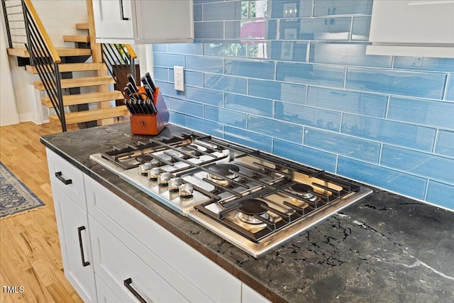 kitchen with light wood-style floors, white cabinetry, stainless steel gas stovetop, and tasteful backsplash