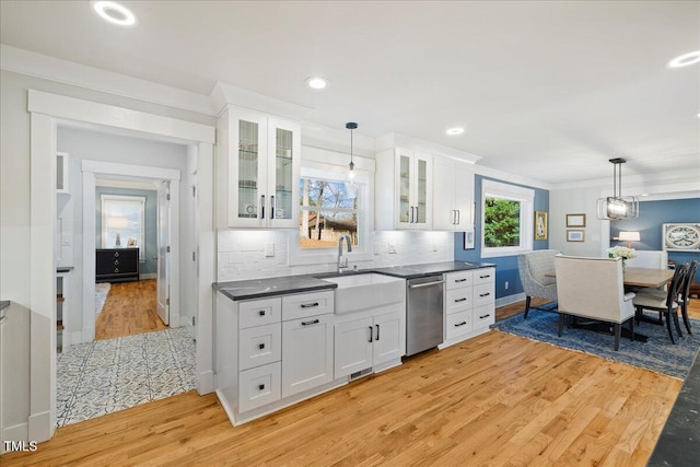 kitchen with white cabinetry, dishwasher, dark countertops, glass insert cabinets, and pendant lighting