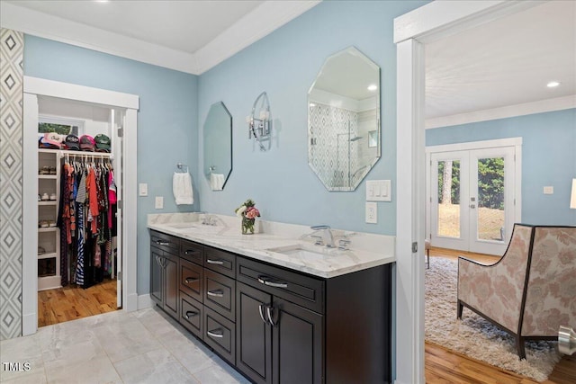 bathroom with double vanity, ornamental molding, a spacious closet, french doors, and a sink