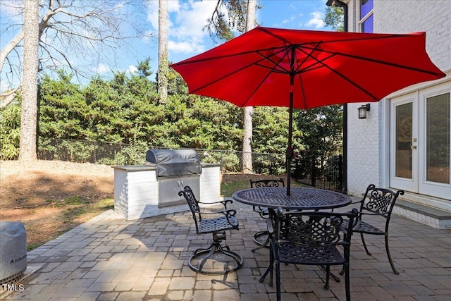 view of patio featuring french doors, fence, grilling area, and an outdoor kitchen