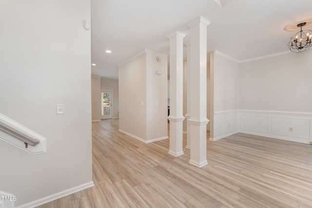 interior space featuring ornamental molding, a decorative wall, light wood-type flooring, and ornate columns