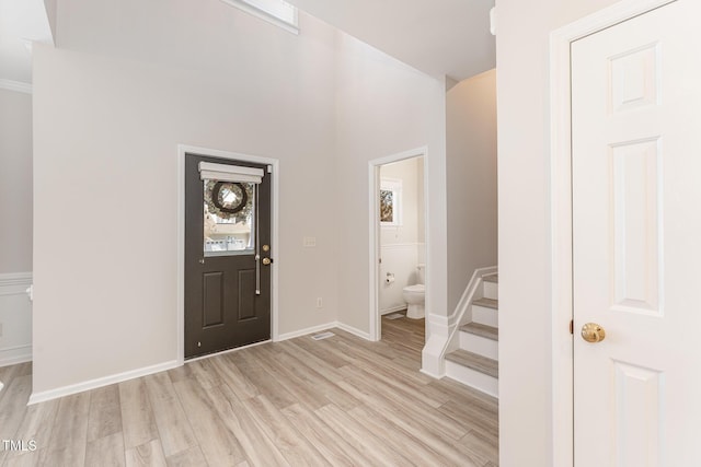 foyer entrance featuring light wood-type flooring, baseboards, and stairs