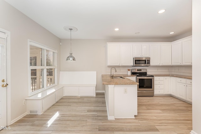 kitchen with stainless steel appliances, a peninsula, a sink, visible vents, and white cabinetry