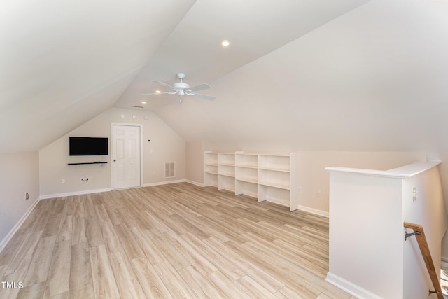 additional living space featuring visible vents, baseboards, a ceiling fan, lofted ceiling, and light wood-style flooring