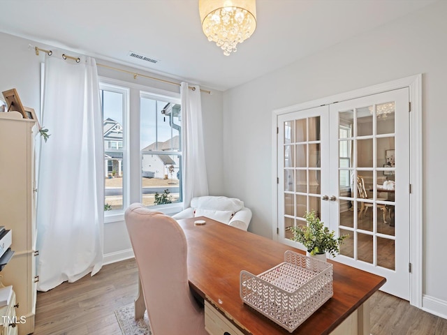 home office featuring light wood-style flooring, visible vents, a chandelier, and french doors