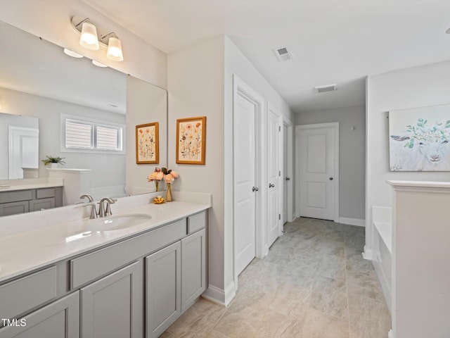 full bathroom with visible vents, baseboards, a bath, and vanity