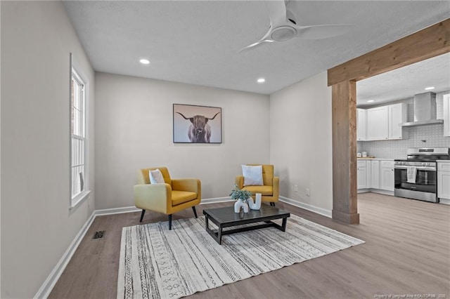 sitting room featuring light wood finished floors, a ceiling fan, visible vents, and baseboards
