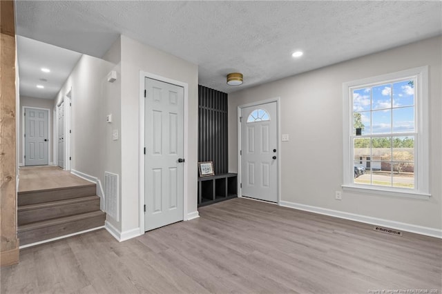 foyer entrance featuring light wood-type flooring, visible vents, and a wealth of natural light