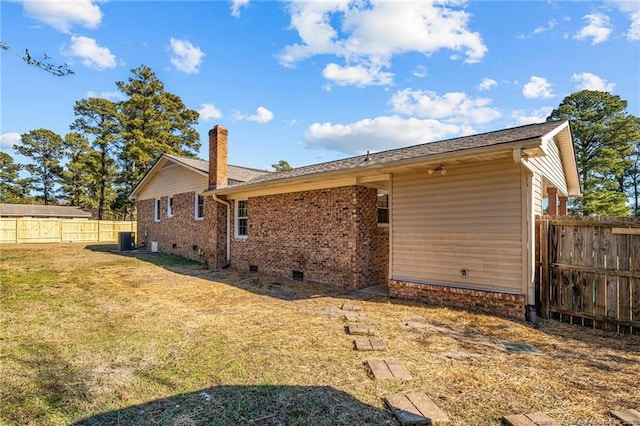 back of house featuring brick siding, a yard, a chimney, crawl space, and a fenced backyard