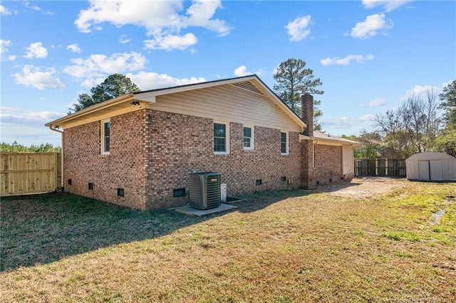 back of house with crawl space, a storage shed, a lawn, and brick siding