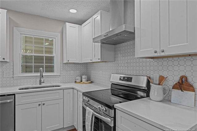 6815 Radial Dr, Fayetteville, NC 28311 - kitchen with stainless steel appliances, wall chimney range hood, light countertops, decorative backsplash, and white cabinets