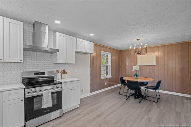 6815 Radial Dr, Fayetteville, NC 28311 - kitchen with stainless steel electric range, wall chimney exhaust hood, light countertops, white cabinetry, and tasteful backsplash