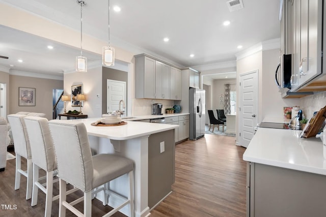 kitchen with a breakfast bar area, gray cabinets, light countertops, hanging light fixtures, and visible vents