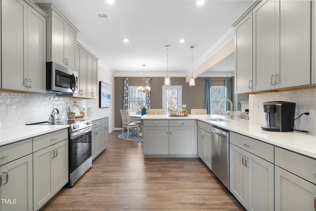 kitchen featuring light countertops, appliances with stainless steel finishes, gray cabinets, and decorative light fixtures