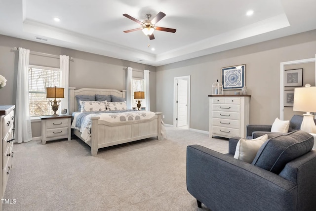 bedroom with a tray ceiling, light carpet, and baseboards