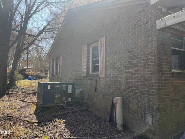 view of side of home featuring central AC and brick siding