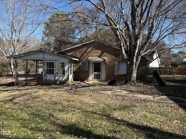 view of front of home with brick siding, a front yard, and fence