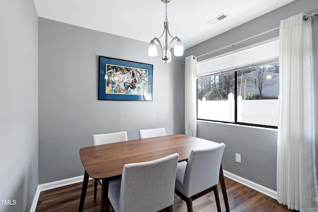 dining space featuring dark wood finished floors, a notable chandelier, visible vents, and baseboards