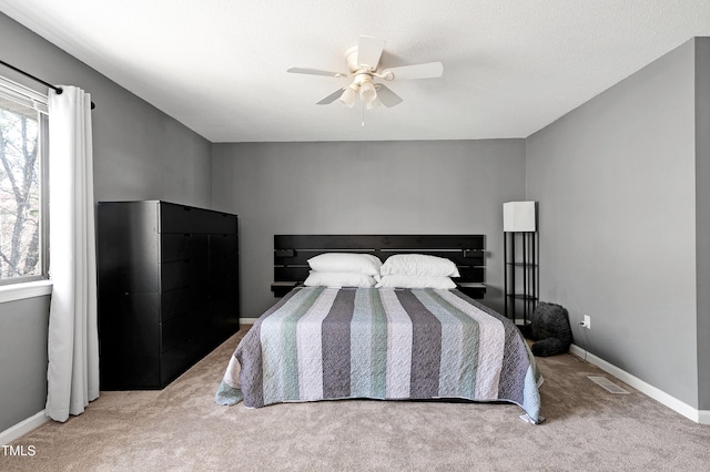 carpeted bedroom with a ceiling fan, multiple windows, baseboards, and visible vents