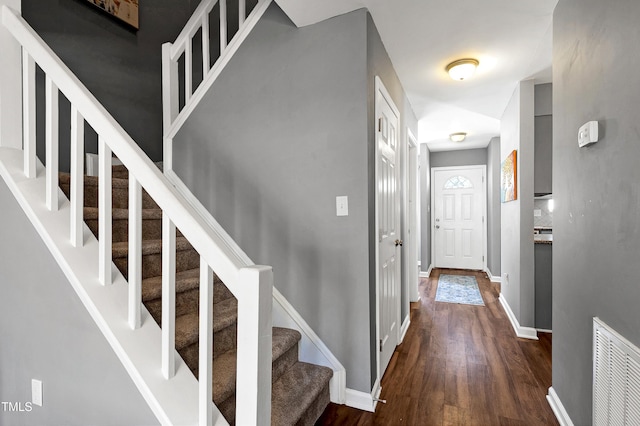 corridor featuring dark wood finished floors, visible vents, stairway, and baseboards