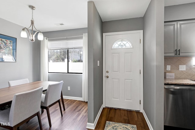 entrance foyer featuring a notable chandelier, visible vents, dark wood-style flooring, and baseboards