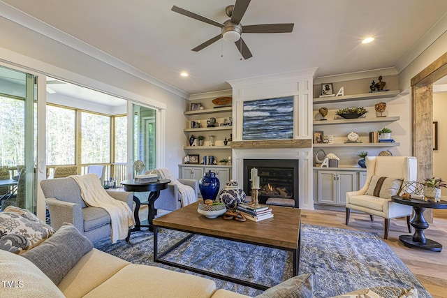 25 Blackhorn Ct, Pittsboro, NC 27312 - living area with built in shelves, a fireplace, a ceiling fan, light wood-style floors, and crown molding