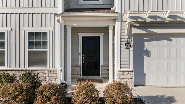 property entrance with a garage, stone siding, and board and batten siding