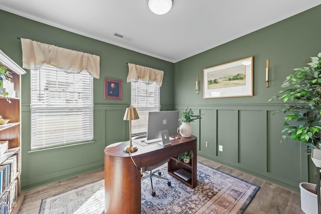 office with a wainscoted wall, visible vents, a decorative wall, and wood finished floors