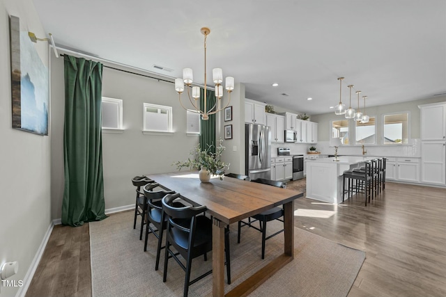 dining space featuring a chandelier, visible vents, light wood-style flooring, and baseboards