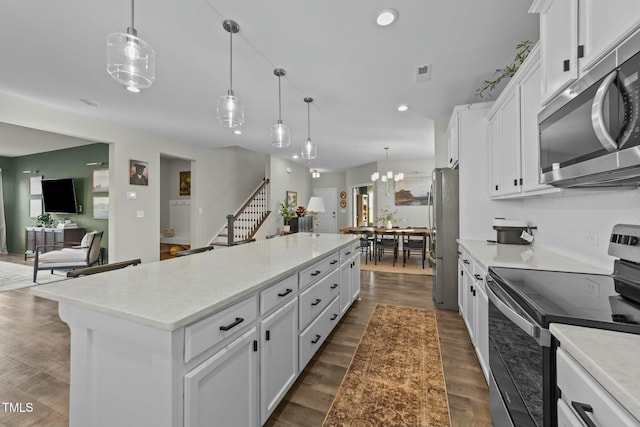 kitchen featuring stainless steel appliances, a center island, pendant lighting, and white cabinets