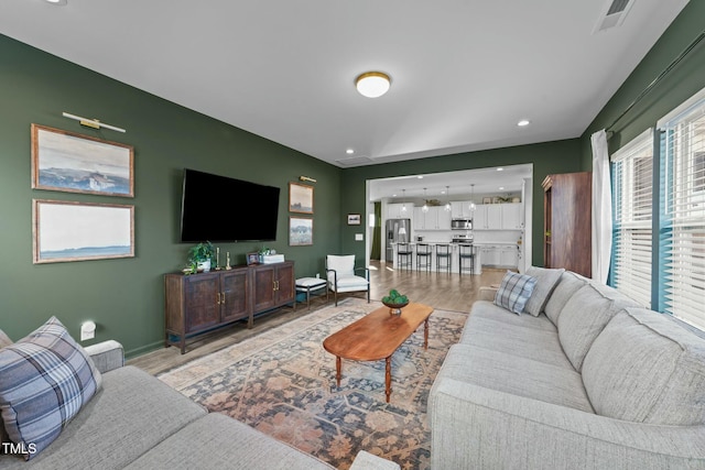 living room featuring light wood finished floors, baseboards, visible vents, and recessed lighting