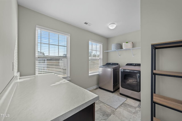 laundry room with laundry area, separate washer and dryer, visible vents, and baseboards