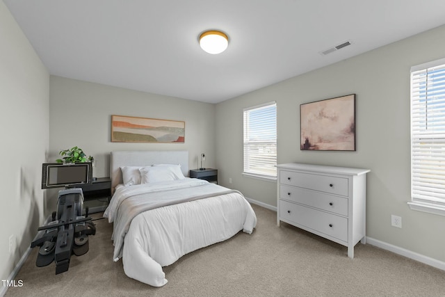 bedroom featuring light carpet, baseboards, multiple windows, and visible vents