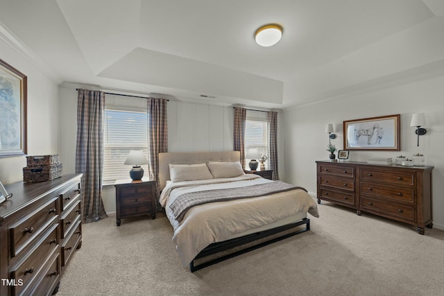 bedroom with ornamental molding, a raised ceiling, visible vents, and light colored carpet