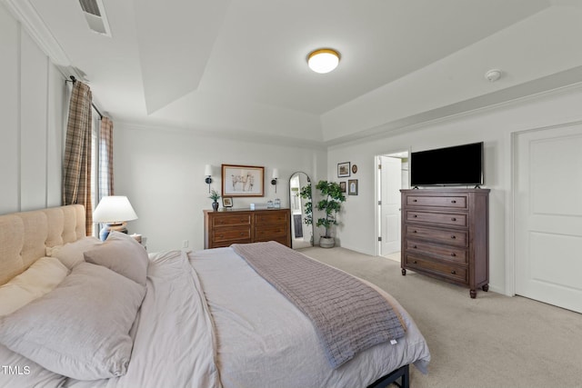 bedroom with light carpet, a tray ceiling, multiple windows, and visible vents