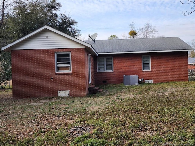 rear view of house with crawl space, central air condition unit, a lawn, and brick siding