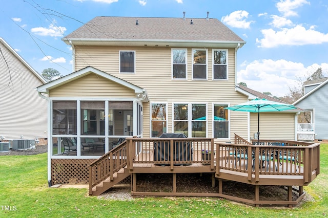 rear view of property featuring central air condition unit, a lawn, a sunroom, and roof with shingles