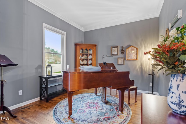 home office with visible vents, crown molding, baseboards, and wood finished floors