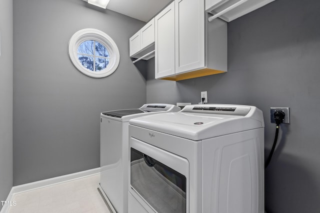 laundry room featuring separate washer and dryer, cabinet space, and baseboards