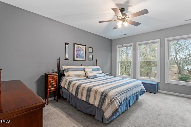 bedroom with ceiling fan, multiple windows, baseboards, and light carpet