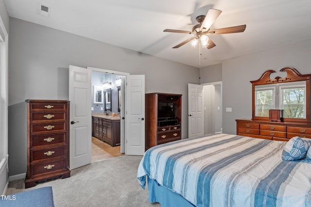 bedroom with ceiling fan, visible vents, light carpet, and ensuite bath