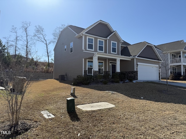 craftsman-style home with a garage, stone siding, and central air condition unit