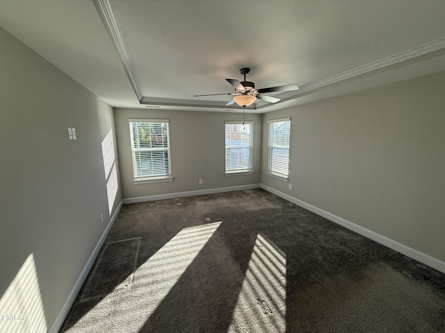 empty room featuring dark colored carpet, a raised ceiling, ceiling fan, and baseboards