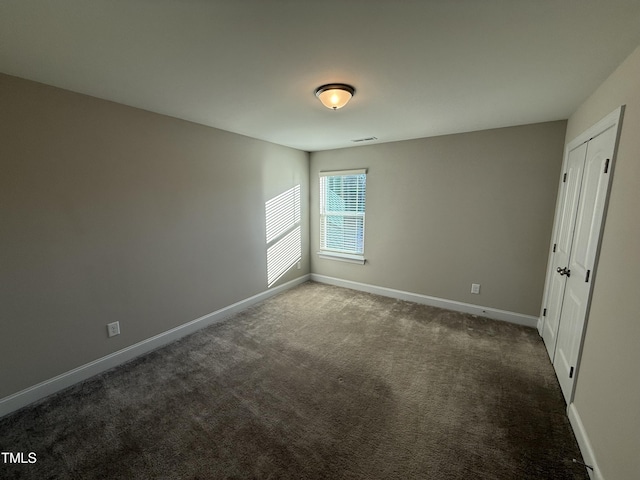 unfurnished bedroom with dark colored carpet and baseboards