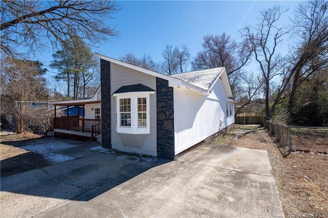 view of home's exterior with covered porch, driveway, and fence