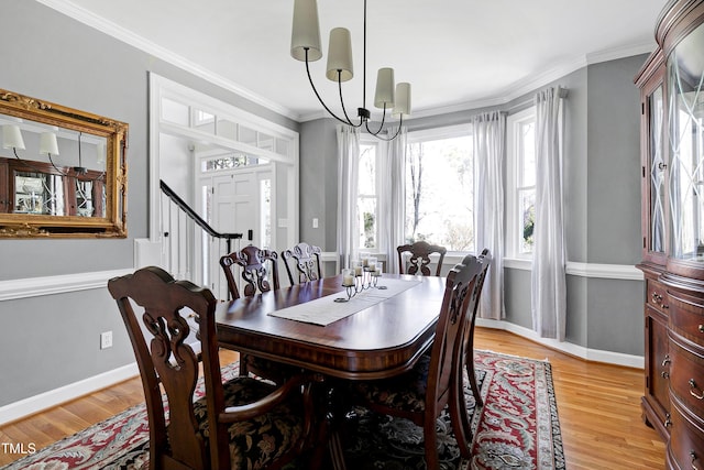 dining space with a chandelier, baseboards, light wood-style floors, and ornamental molding