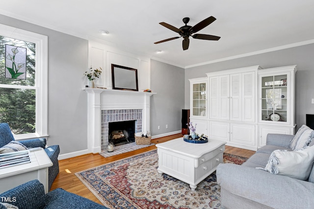 living room with baseboards, light wood-style floors, ornamental molding, and a ceiling fan